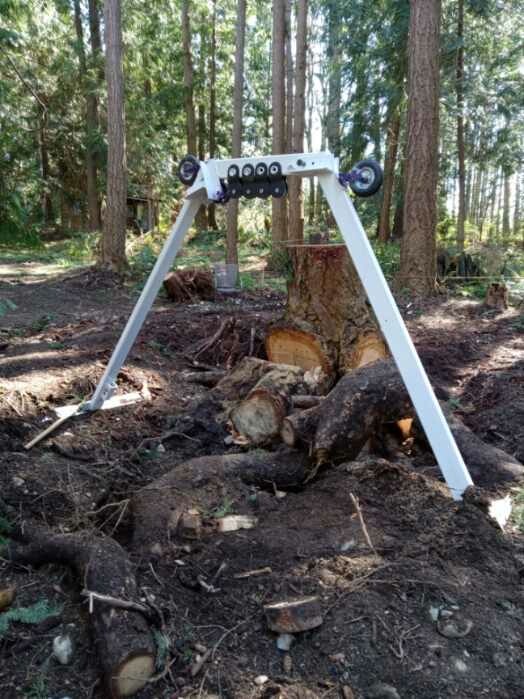 Custom white A-frame puller positioned over a large stump